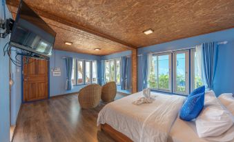 a bedroom with a large bed , blue walls , and a view of the ocean through a window at Seafar Resort