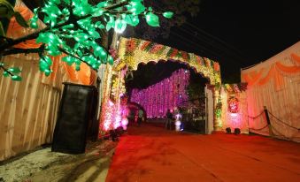 a grand entrance decorated with flowers and lights , leading to a red carpet with people walking through at Hotel Samrat