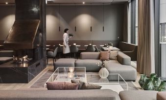 a modern living room with gray sofas , a glass coffee table , and a person standing in the background at Hotel Odeon