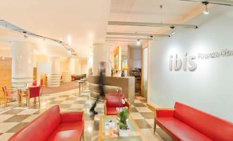 a lobby area with red couches and chairs , a reception desk , and a glass display case at Ibis Firenze Nord Aeroporto