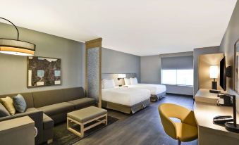 a modern hotel room with two beds , a couch , and a dining table , all arranged in a spacious layout at Hyatt Place Fresno