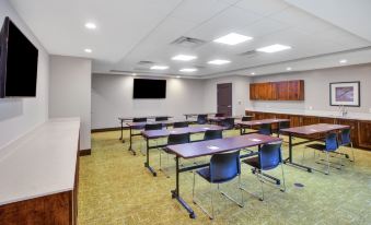 a conference room with several tables and chairs , a television on the wall , and a podium at Staybridge Suites Benton Harbor - ST. Joseph