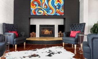 a modern living room with a large fireplace , black walls , and a colorful abstract painting above the fireplace at Berry Village Boutique Motel