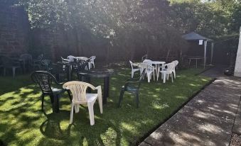 an outdoor dining area with several white plastic chairs and tables set up in a grassy area at The George Hotel