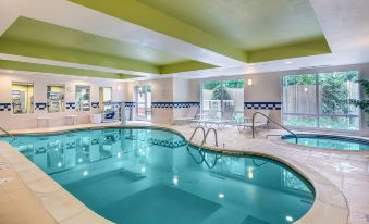 a large swimming pool with a diving board and lounge chairs is surrounded by a green ceiling at Fairfield Inn & Suites Worcester Auburn
