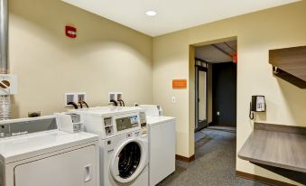 a laundry room with three washing machines and a dryer , as well as a door leading to another room at Home2 Suites by Hilton Dickson City Scranton