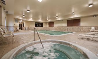 a large indoor pool area with multiple hot tubs and a jacuzzi , surrounded by chairs and tables at Homewood Suites by Hilton Rochester - Victor