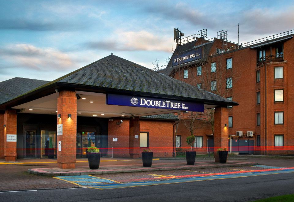 the exterior of a doubletree hotel with a large sign above the entrance , and a building on the left side at DoubleTree by Hilton Manchester Airport