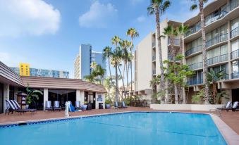a large swimming pool surrounded by palm trees and buildings , with people enjoying their time in the water at Wyndham San Diego Bayside