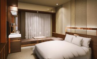 a large bed with white sheets is in a room with a sink and a window at Candeo Hotels Omiya