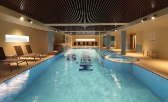 a long , narrow swimming pool with blue water and chinese characters on the walls is surrounded by lounge chairs and a ceiling at Grand Hotel Misurina