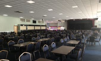 a large , empty room with rows of tables and chairs , and a stage at the end at North Devon Resort