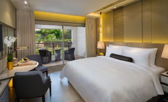 a large , white bed is in a room with a sliding glass door leading to an outdoor patio at Kempinski Summerland Hotel & Resort Beirut