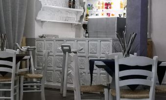 a restaurant with white tables and chairs , a bar counter , and bottles on shelves behind the counter at Hotel Panorama