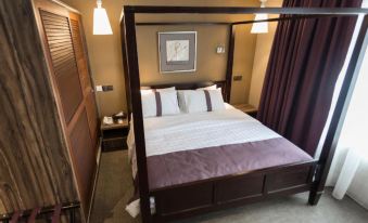 a large bed with a wooden canopy is in a room with brown curtains and a purple wall at Z Hotel
