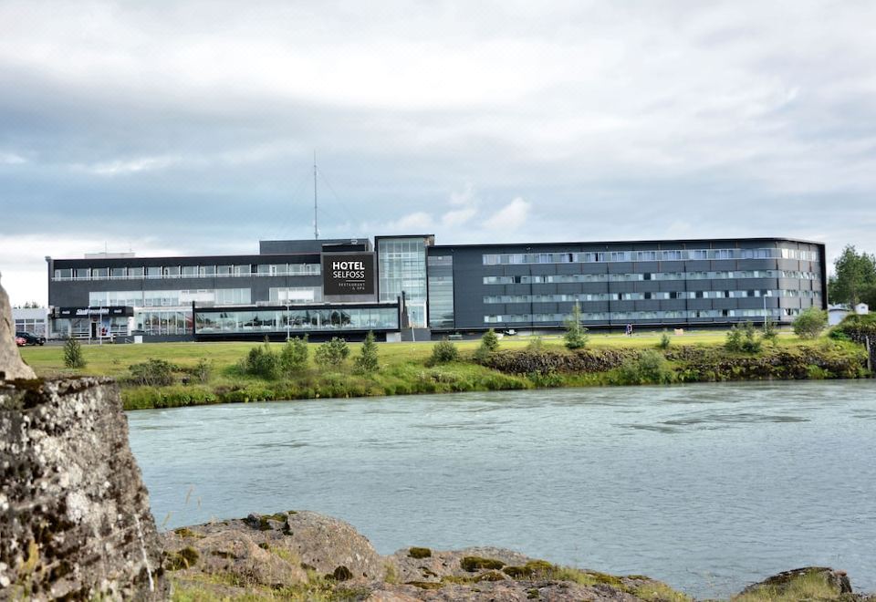 a large building with a sign on the side is situated next to a river at Hotel Selfoss