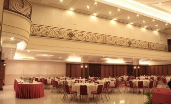 a large banquet hall with multiple dining tables and chairs set up for a formal event at Luminor Hotel Jember by WH