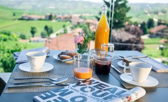 a table set with breakfast items , including coffee , juice , and a newspaper , on a balcony overlooking a scenic view at Arborina Relais