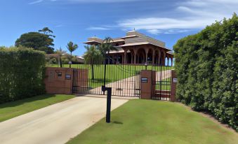 a large house with a red roof and wooden pillars is surrounded by greenery and a gate at Jodha Bai Retreat