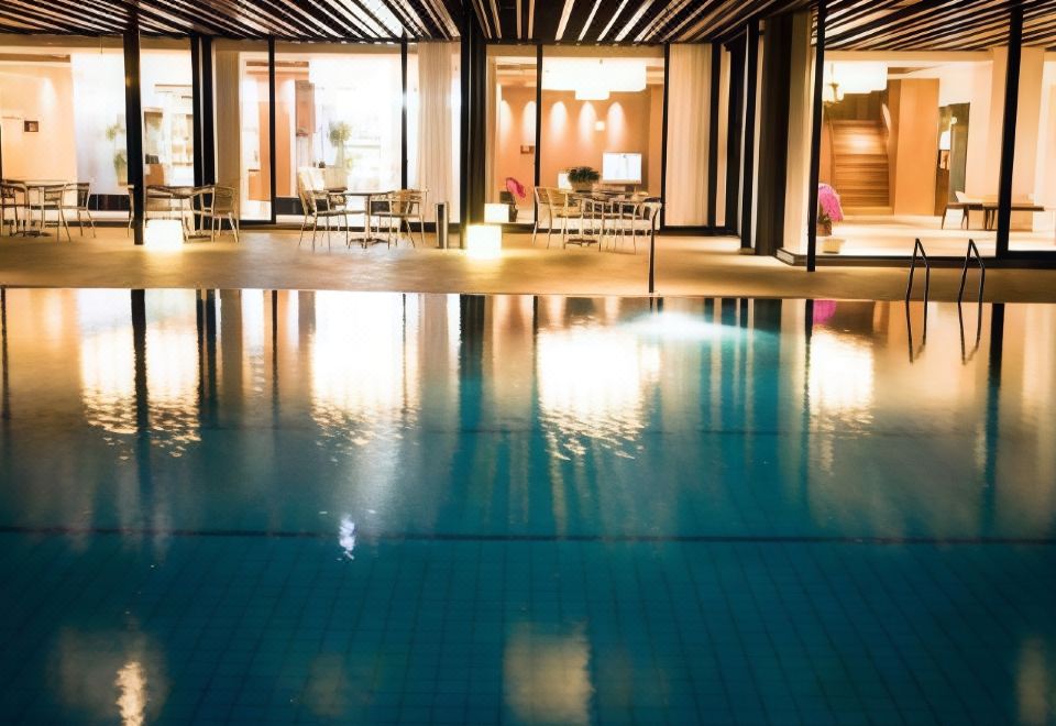 an indoor swimming pool surrounded by a lounge area , with chairs and tables placed around the pool at Hotel Fuji