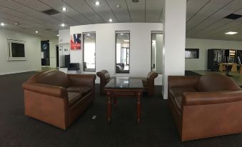 a modern office space with leather couches and chairs arranged in a comfortable sitting area at FairBridge Inn Express Melrose Park