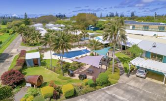 aerial view of a resort with a pool surrounded by palm trees and lush greenery at Aloha Apartments