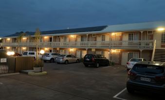 a nighttime scene of a hotel with multiple cars parked in the parking lot , under the blue sky at Motel Goolwa