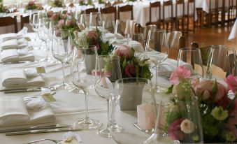 a long dining table with white tablecloth and multiple wine glasses filled with pink and white flowers at Dialoghotel Eckstein
