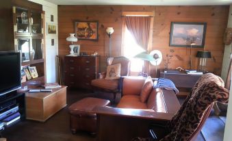 a cozy living room with wooden walls , brown furniture , and various pieces of furniture arranged around the room at Seventy-Four Ranch