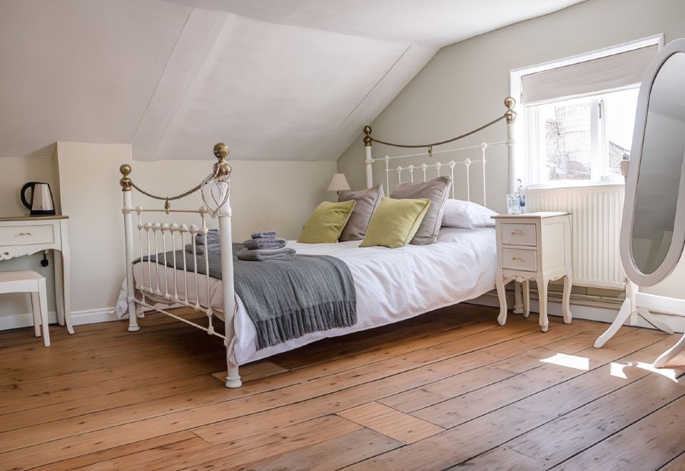 a white bed with a metal frame is situated in a room with wooden floors and walls at The Golden Key