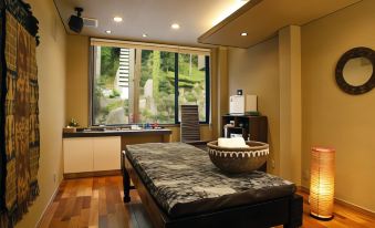 a modern , minimalist room with wooden floors and large windows , featuring a bed with a black patterned cushion and a small table at Fuefukigawa Onsen Zabou