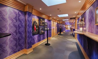 a hallway with purple walls and a gray floor , featuring pictures on the walls and a lighted ceiling at Quality Hotel Grand Kongsberg