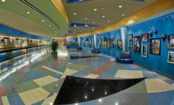 a large , well - lit hotel lobby with a blue and yellow color scheme , showcasing various pieces of furniture and artwork at Disney's Pop Century Resort - Classic Years