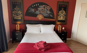 a modern bedroom with red walls , white bedding , and black and white feng shui artwork on the walls at Tambaridge Bed & Breakfast