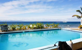 a man is taking a photo of a swimming pool with the ocean in the background at Beachcomber Island Resort