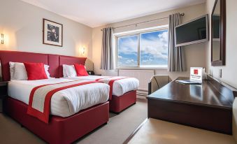 a hotel room with two beds , a desk , and a window , all decorated in red and white colors at Peartree Lodge Waterside