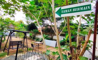 "a green street sign with the words "" taman berawa "" is displayed in front of a tropical garden" at Bakom Inn Syariah