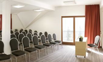 a conference room with rows of chairs arranged in a semicircle and a podium at the front at Ahotel Ljubljana