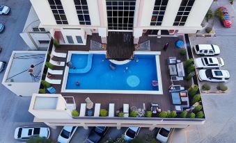 an aerial view of a rooftop pool with people in the water and lounge chairs at Royal View Hotel
