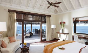 a luxurious bedroom with a view of the ocean , featuring a king - sized bed , a ceiling fan , and a door leading to a balcony at Taj Exotica Resort & Spa
