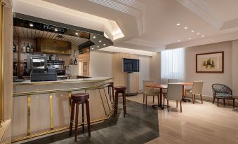 a modern bar area with a white countertop , gold stools , and a television mounted on the wall at Exe Salamanca