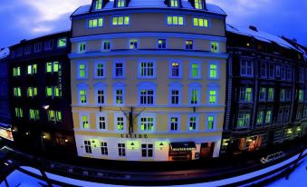a large , white building with green lights and a blue sign in front of it at Hotel Sailer