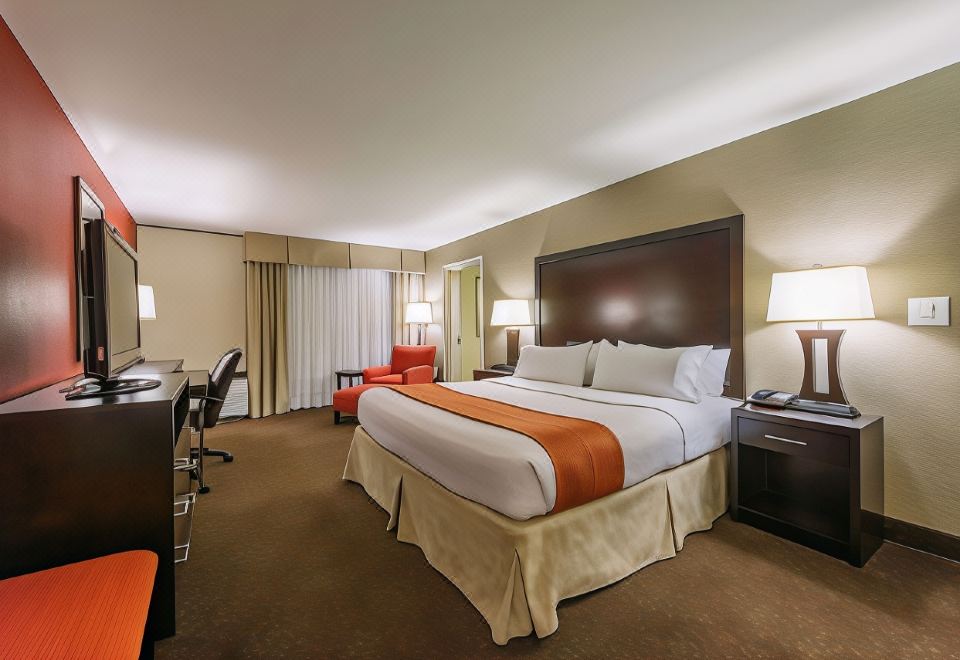 a large bed with white sheets and an orange blanket is in the middle of a hotel room at Hotel Mtk Mount Kisco