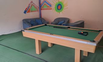 a pool table is in the center of a room with chairs and a chandelier at Hidden Inn