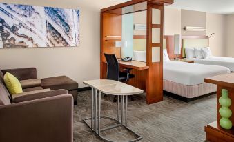 a modern hotel room with a desk , chair , and bed , as well as a couch and coffee table at SpringHill Suites Long Island Brookhaven