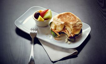 a plate with a sandwich , fruit , and a fork is placed on a table next to a napkin at Courtyard Rochester Brighton