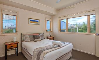 a bedroom with a large bed , two nightstands , and a window overlooking a beautiful view at Hastings Cove Holiday Apartments