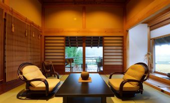 a room with a wooden ceiling and walls , featuring two chairs , a table , and a large window at Shouen