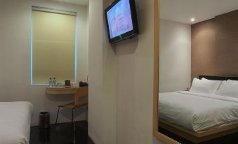a hotel room with a television mounted on the wall and a bed in the corner at M Hotel