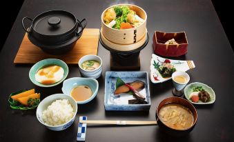 a table is filled with various dishes , including rice , soup , and soup bowls , along with chopsticks at Shima Onsen Kashiwaya Ryokan